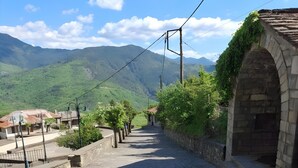 A cobblestone street with a stone bridge, greenery, and distant mountains. - Guest House 'Armoloi Room 2' with Mountain View, Shared Terrace and Wi-Fi (Konitsa)
