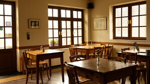 A room with multiple wooden tables and chairs, large windows with frosted glass, a wall-mounted speaker, and a framed picture. - Guest House 'Armoloi Room 6' with Mountain View, Shared Terrace and Wi-Fi (Konitsa)