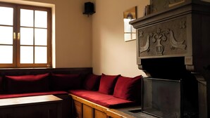 A room with a wooden bench, a fireplace with decorative carvings, and a window with multiple panes. - Guest House 'Armoloi Room 6' with Mountain View, Shared Terrace and Wi-Fi (Konitsa)