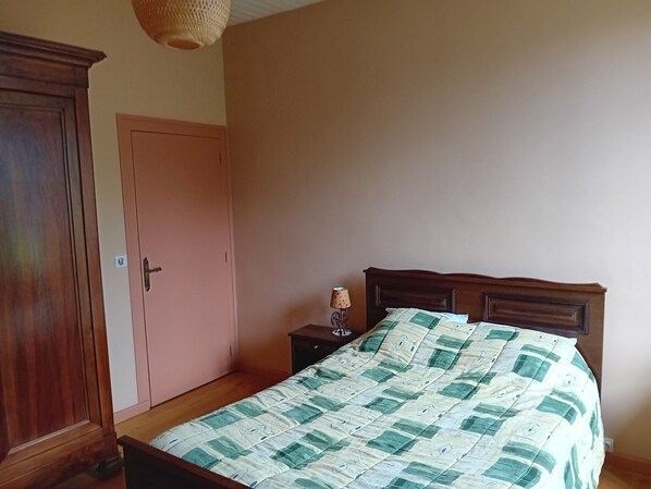 Un dormitorio con una cama y un armario de madera, y una puerta.