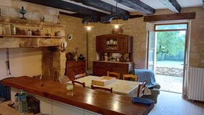 Eine rustikale Küche mit Holzregalen, einem Esstisch und Blick ins Freie.