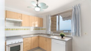 Una cocina moderna con armarios de madera, horno integrado, lavavajillas y una ventana con cortinas.
