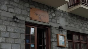 Edifici de pedra amb un tauleller, baranes de balcó de fusta i una taula amb caires a l'exterior.