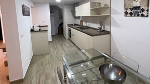 A modern kitchen with a glass dining table, stainless steel appliances, and a small island. - Rural House 'La Morena' with Mountain Views, Wi-Fi, and Air Conditioning (Guaro)