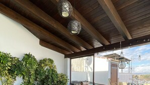 An outdoor seating area with a sofa, chairs, and a table, surrounded by greenery and a view of the city. - Rural House 'La Morena' with Mountain Views, Wi-Fi, and Air Conditioning (Guaro)