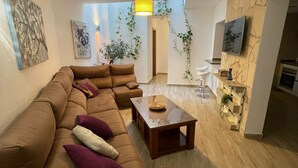 A living room with a sectional sofa, a coffee table, and a TV mounted on the wall. - Rural House 'La Morena' with Mountain Views, Wi-Fi, and Air Conditioning (Guaro)