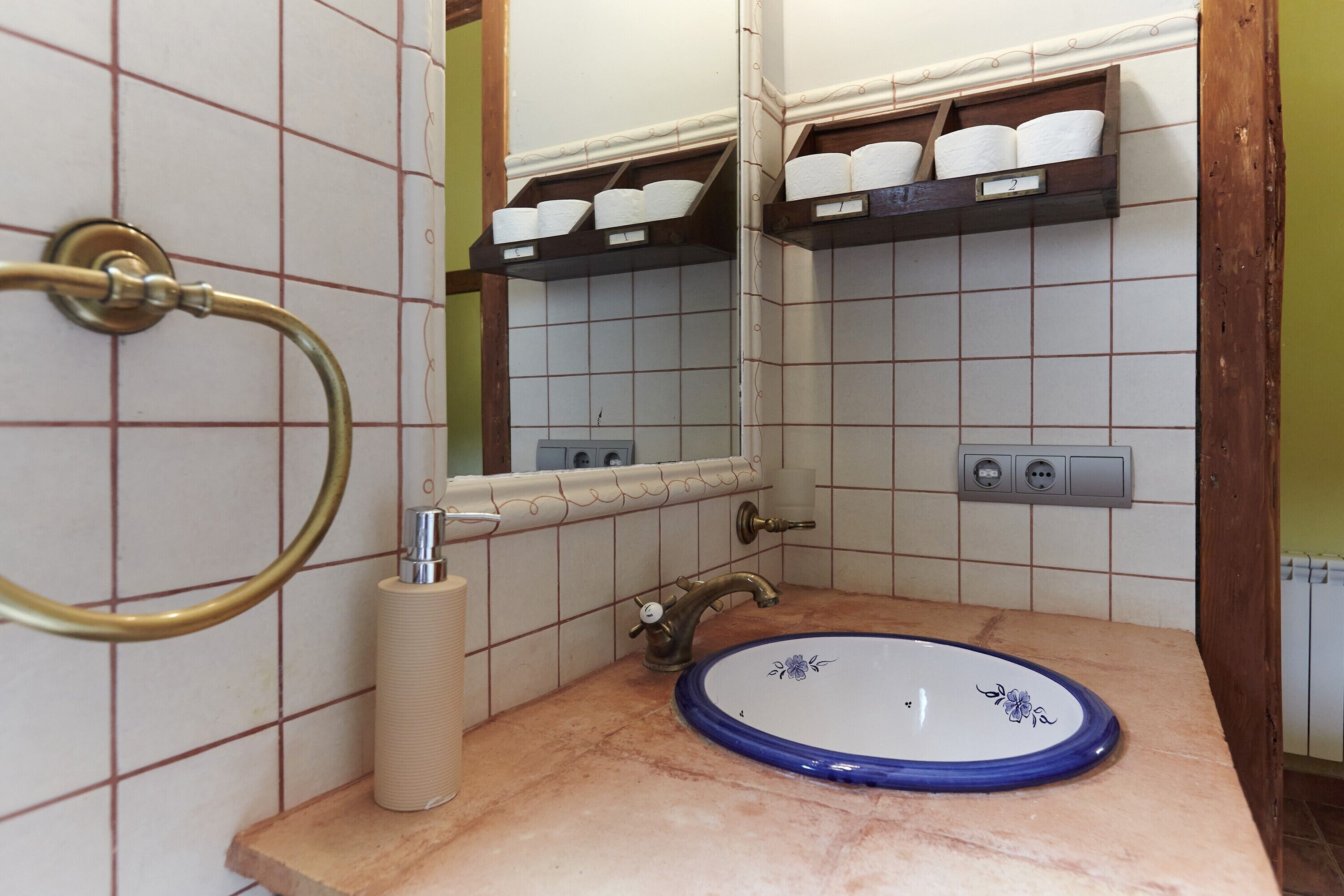 Un bagno con lavandino, specchio, portascopevoli e mensole con articoli da toilette.
