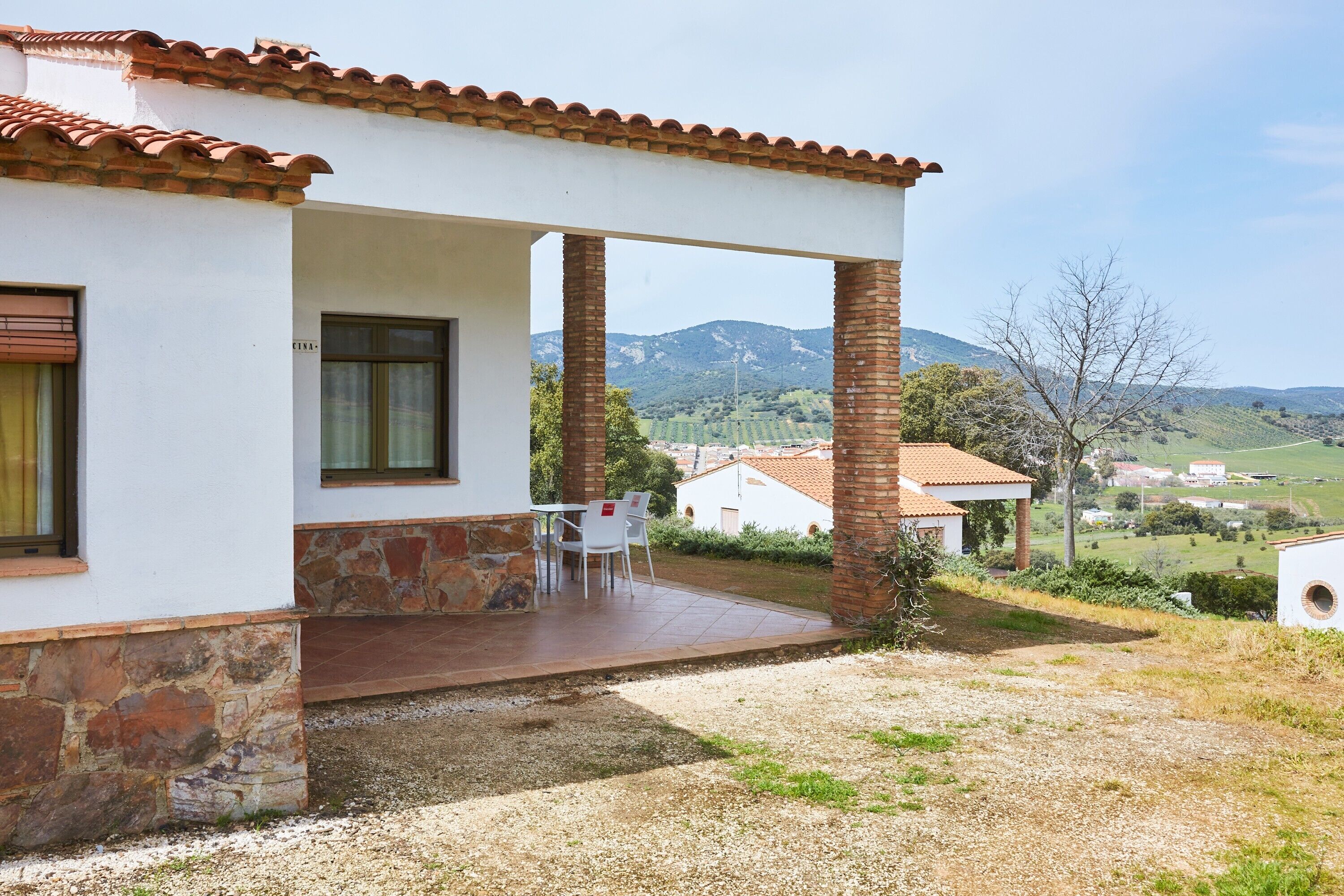 Une maison dotée d’un patio couvert, de fondations en pierre et offrant une vue sur un paysage vallonné.