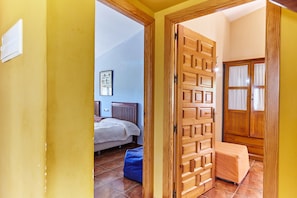 A bedroom with a bed, a blue bean bag, a wooden wardrobe, and a door leading to another room.