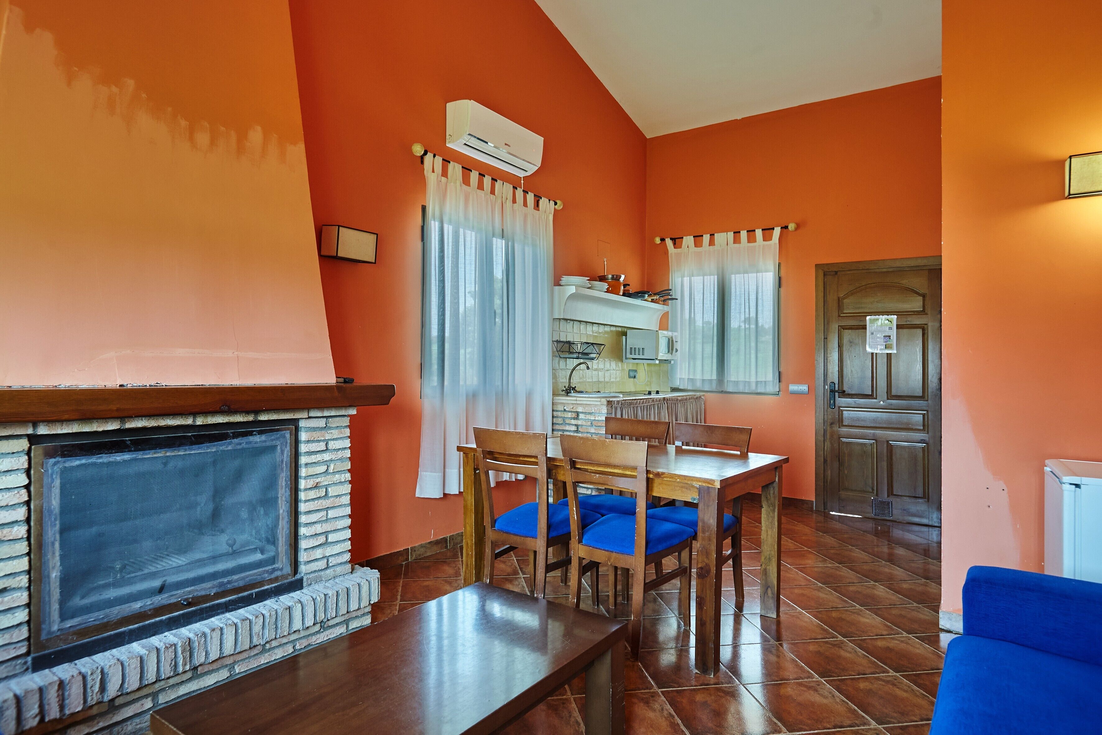 Una sala de estar con chimenea, mesa de comedor, sillas y sofá.