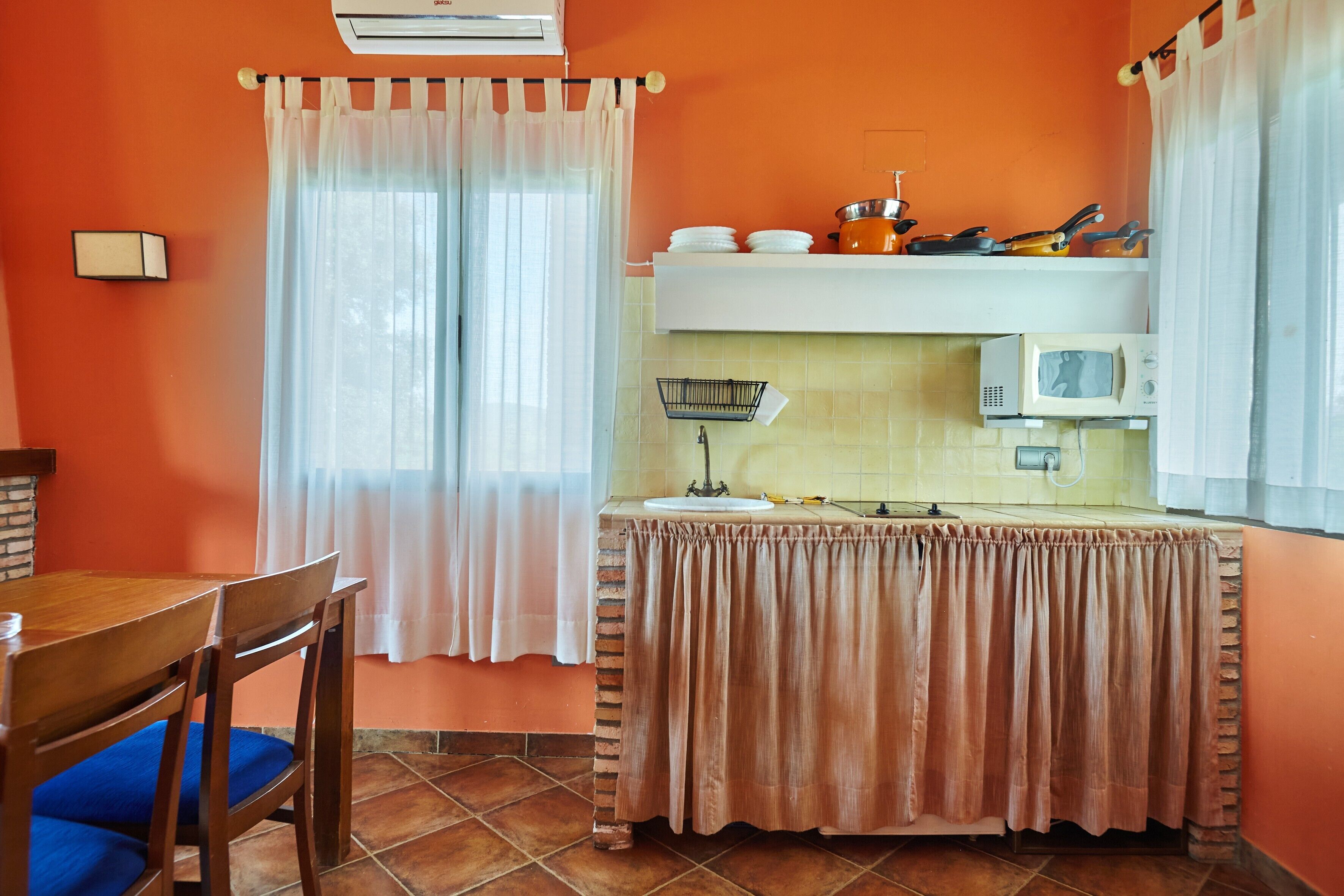Una cocina con una mesa, sillas, microondas y un lavamanos.