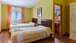 A room with two beds, a bathroom with a sink, and a door leading to another room. - Country House 'Casa El Águila' with Mountain View, Shared Pool and Air Conditioning (ALDEAQUEMADA)
