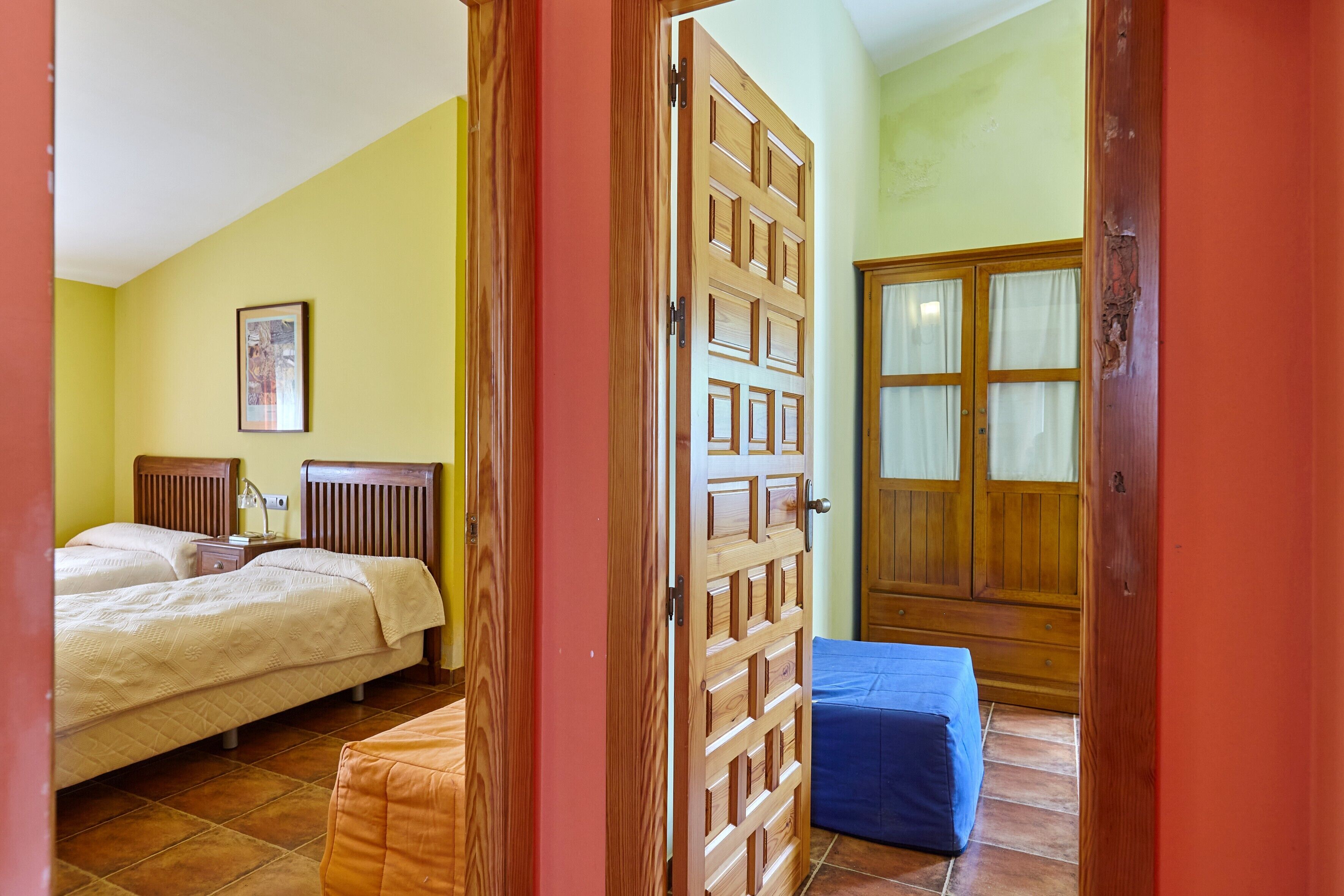 Un dormitorio con dos camas, una puerta de madera y un ventanal con cortinas.