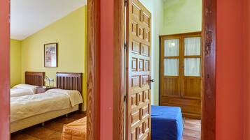 Un dormitorio con dos camas, una puerta de madera y un ventanal con cortinas.