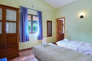 Ein Schlafzimmer mit zwei Betten, einem Holzschrank, einem Fenster mit Vorhängen und einer Wandleuchte.
