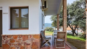A patio with a stone wall, a window, and a table with chairs. - Country House 'Casa El Águila' with Mountain View, Shared Pool and Air Conditioning (ALDEAQUEMADA)