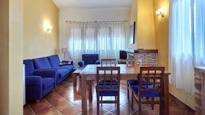 A living room with a sofa, chairs, a table, and a TV.