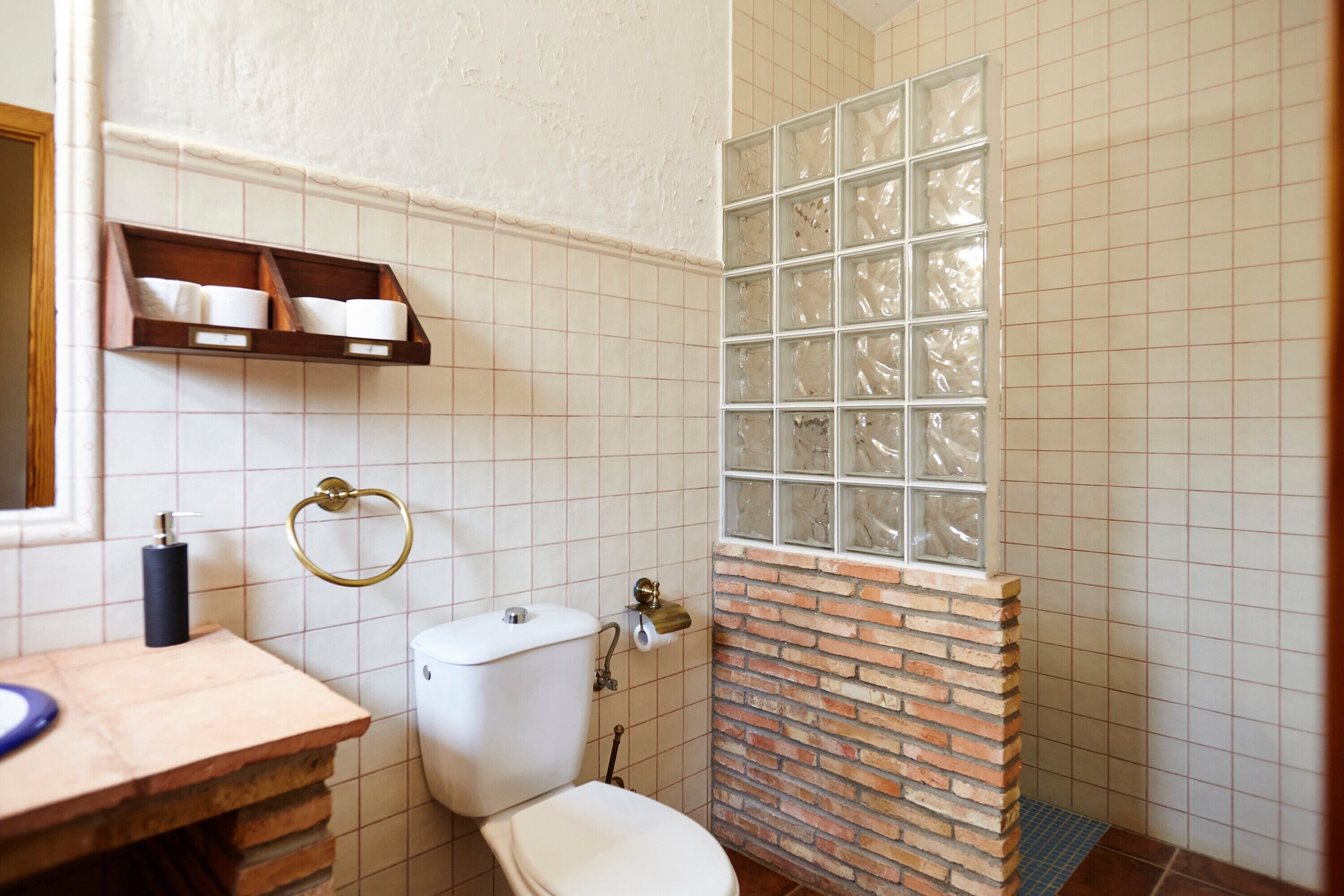Et badeværelse med toilet, håndvask og bruseområde med brusekabine.