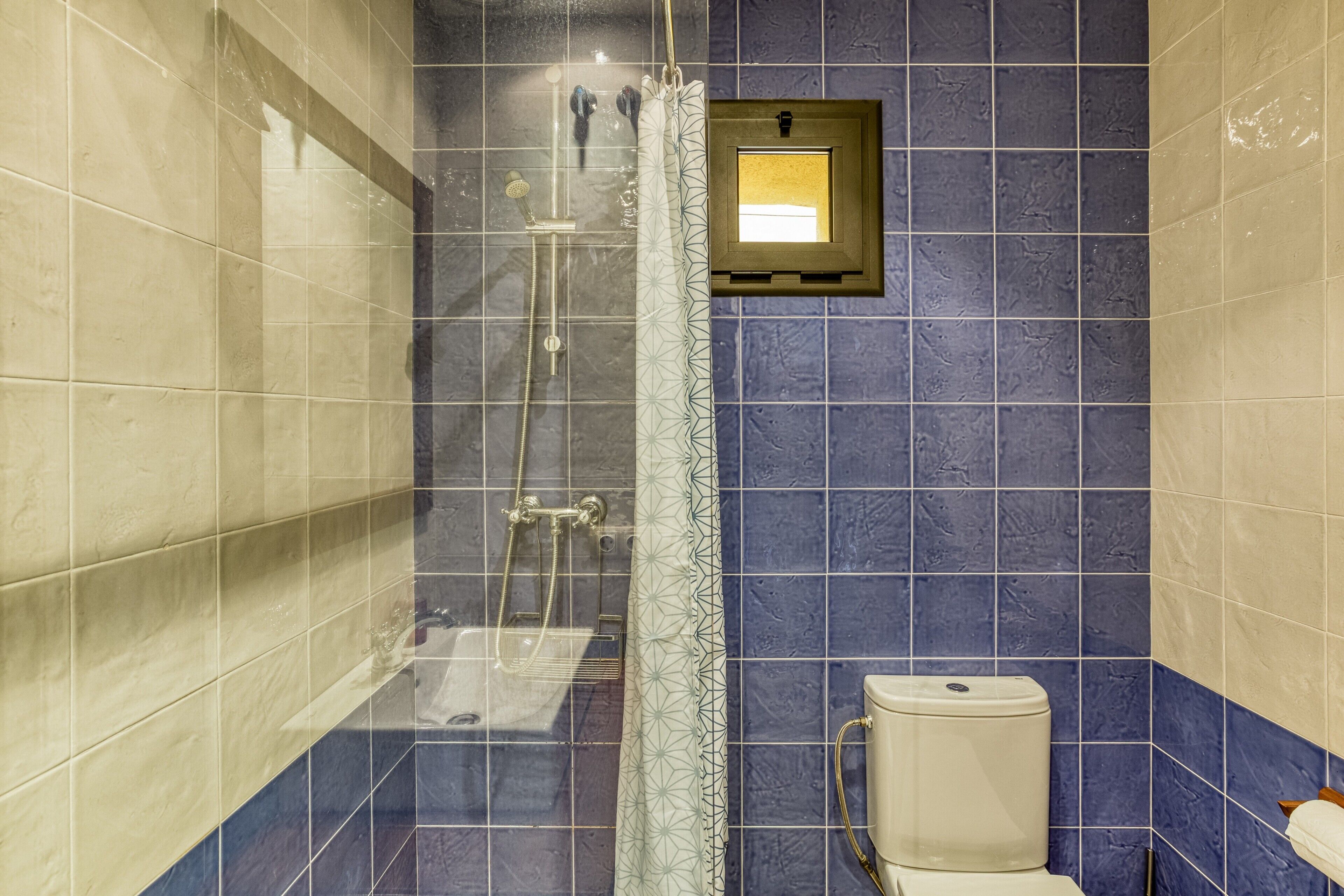 A bathroom with a glass-enclosed shower, a toilet, and a small mirror.