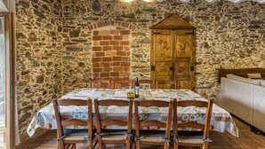 Una habitación de paredes de piedra con chimenea de ladrillo, muebles de madera y una mesa dispuesta para comer.