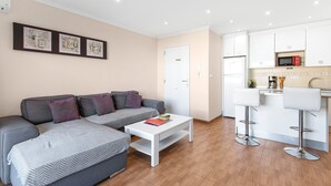 A modern living room with a sofa, a coffee table, and a kitchen area with white cabinets and a microwave. - Apartment 'Yovalu Con Balcon' with Balcony, Wi-Fi and Air Conditioning (Torrevieja)