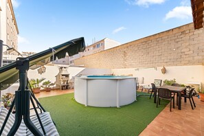 Un jacuzzi rond, entouré d’une terrasse aménagée avec une table, des chaises, un télescope et des plantes en pot.