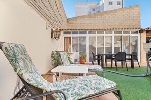 A patio with two lounge chairs, a small table, and a dining area with chairs and a table.