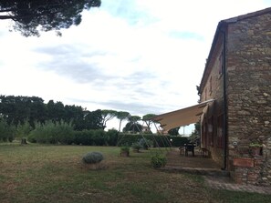 A stone building with a patio, outdoor furniture, and a swing set.