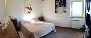 Un dormitorio con cama, un radiador, una ventana y dos carteles en la pared.