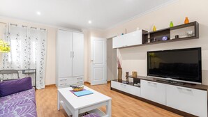 A modern living room with a sofa, a coffee table, a TV, a cabinet, and a door.