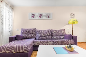A living room with a purple sofa, a white coffee table, and a floor lamp.