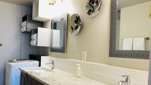 Une salle de bain moderne avec deux lavabos, un grand miroir et un porte-serviettes.