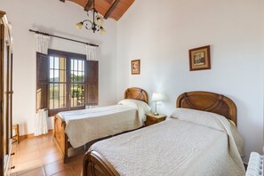 Une pièce avec deux lits en bois, une fenêtre avec des rideaux, un plafond en bois et une petite table de chevet avec une lampe.