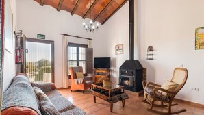 Een woonkamer met een bank, een schommelstoel, een open haard, een televisie en een bord met een nooduitgang.