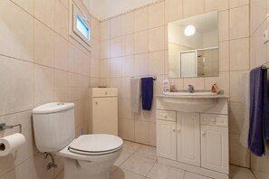 A bathroom with a toilet, sink, cabinet, and mirror.