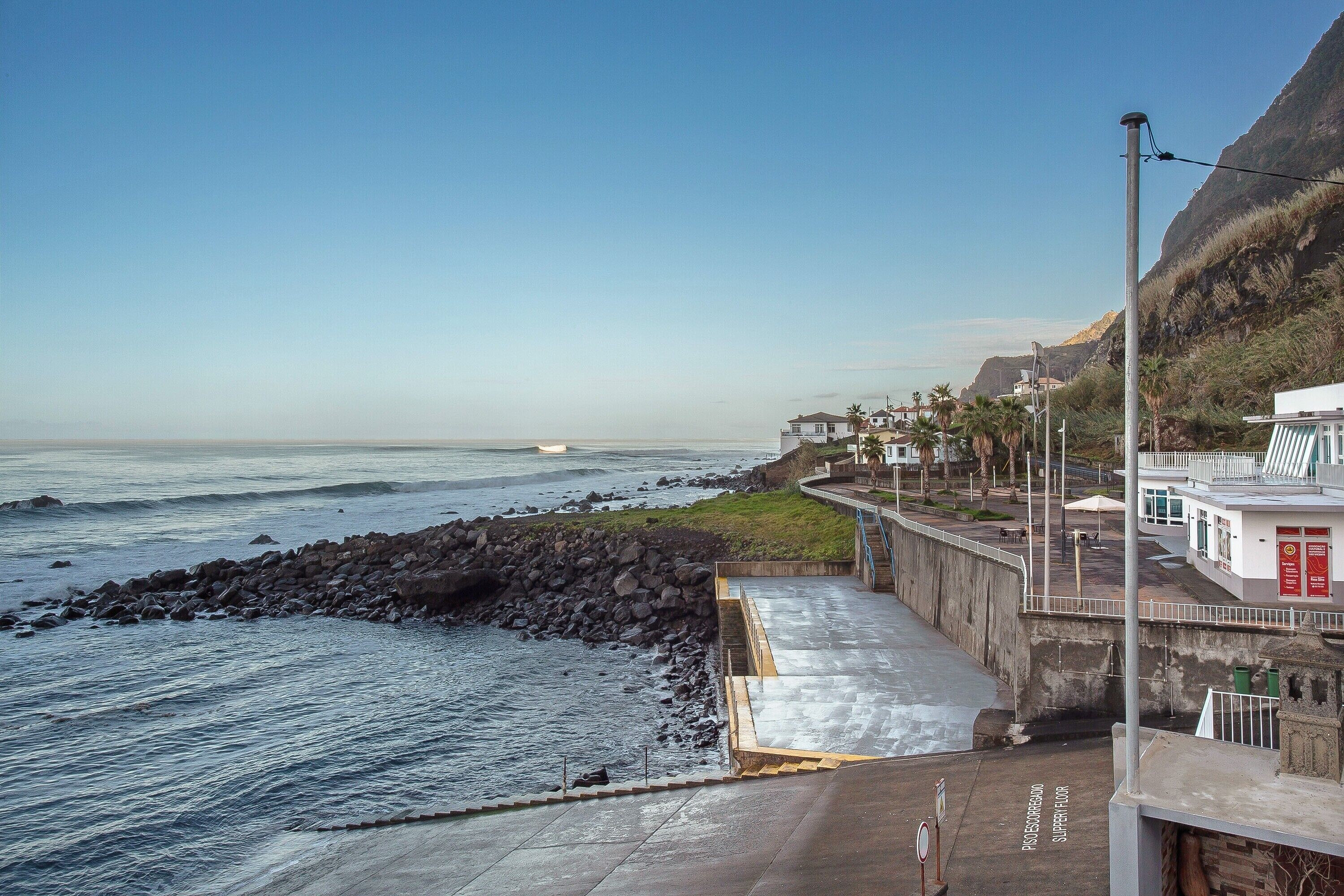 Une promenade en bord de mer offrant une vue sur l’océan, une côte rocheuse et des bâtiments qui bordent le sentier.