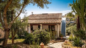 A villa with a tiled roof, stone pathway, and surrounding vegetation. - Villa 'Ines' with Private Pool, Wi-Fi and Air Conditioning (Illes Balears)