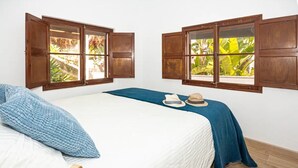 A bedroom with a bed, two windows with wooden shutters, a blue blanket, and a hat on the bed. - Villa 'Ines' with Private Pool, Wi-Fi and Air Conditioning (Illes Balears)