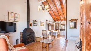 Una sala de estar acogedora con chimenea, televisión y comedor con sillas y mesa.