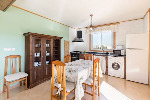 Une cuisine équipée d’une table à manger, de chaises, d’un meuble de rangement, d’un lave-linge et d’un four à micro-ondes.