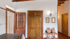 Ein Zimmer mit Holztür, einem Tisch mit gemustertem Tischläufer und zwei Vasen auf einem Sockel.