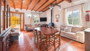 Ein geräumiger Wohnbereich mit Holztisch, Sofas und Fernseher.