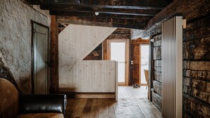A rustic wooden interior with a sloped ceiling, a wooden bench, a door, and a view through an open doorway. - Room 'Stùä' with Mountain View, Shared Terrace and Wi-Fi (Dosoledo)