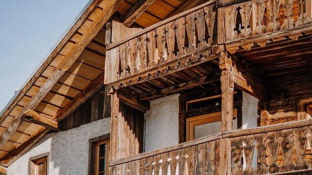A rustic building with a wooden balcony, a large wooden door, and multiple windows. - Room 'Stùä' with Mountain View, Shared Terrace and Wi-Fi (Dosoledo)