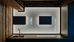 A modern kitchen with a built-in sink, wooden beams, and two illuminated wall panels. - Room 'Stùä' with Mountain View, Shared Terrace and Wi-Fi (Dosoledo)