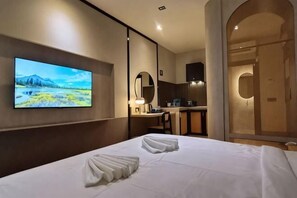 A hotel room with a bed, a TV mounted on the wall, a mirror, and a shower area. - Urban Inn, SP Saujana (Sungai Petani)