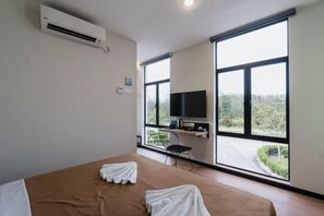 A room with a bed, a TV, and a large window with a view of greenery. - Urban Inn, SP Saujana (Sungai Petani)