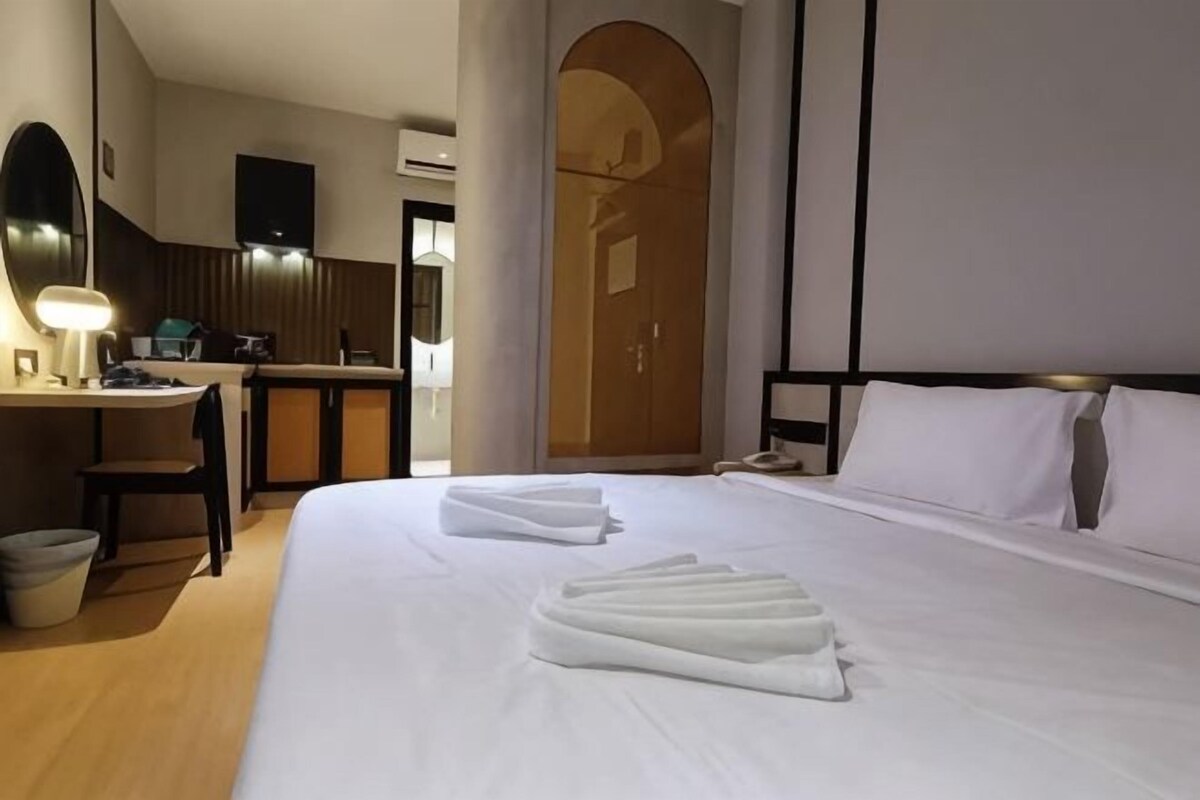 Ein Hotelzimmer mit einem Bett, einem Schreibtisch, einem Stuhl, einem Spiegel und einer Tür.