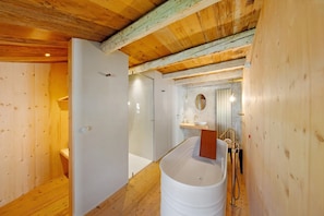 Un interior de madera con una bañera, un lavabo y una ducha.