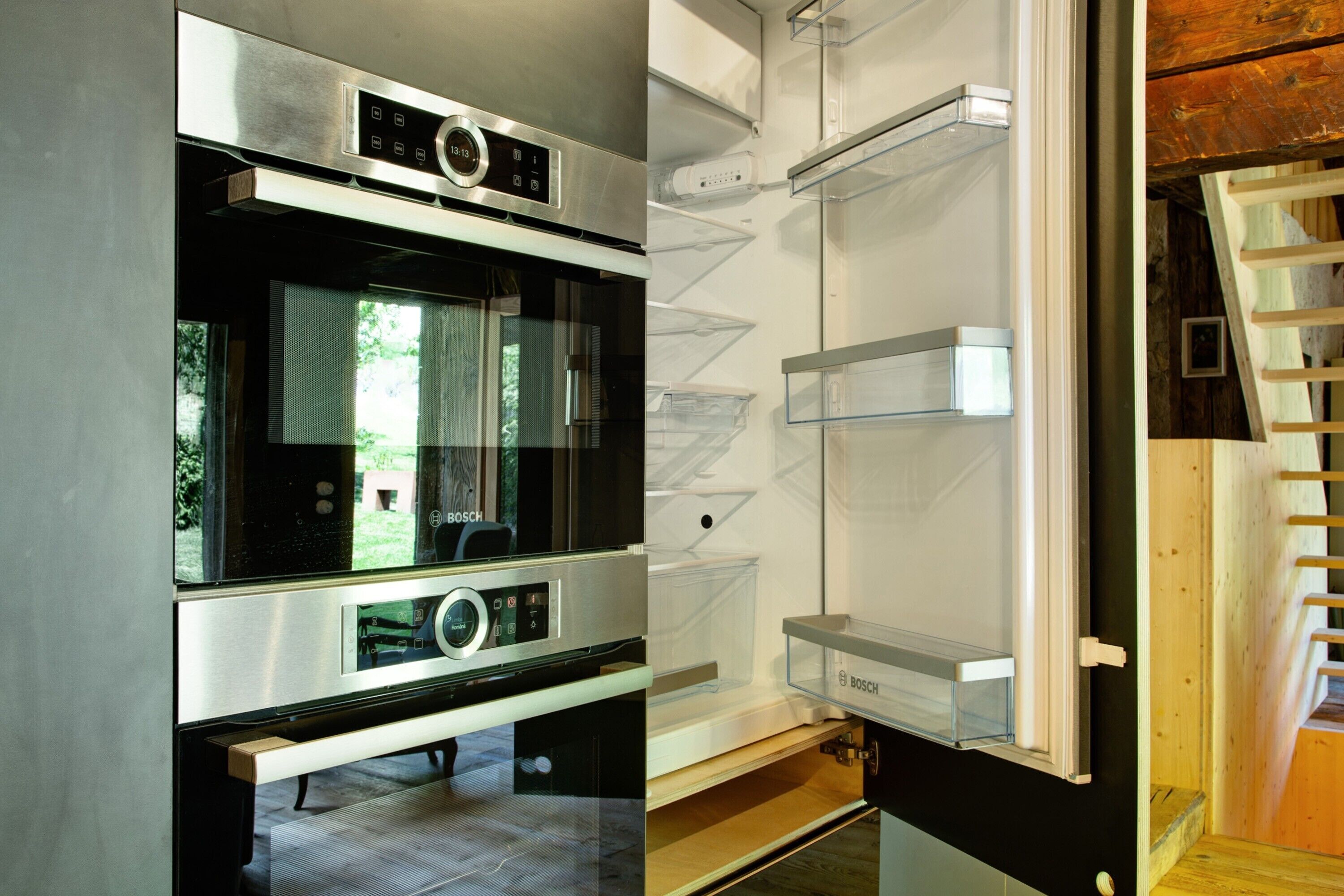 Eine moderne Küche mit einem Kühlschrank von Bosch, einem Edelstahlbackofen und einem integrierten Fenster.